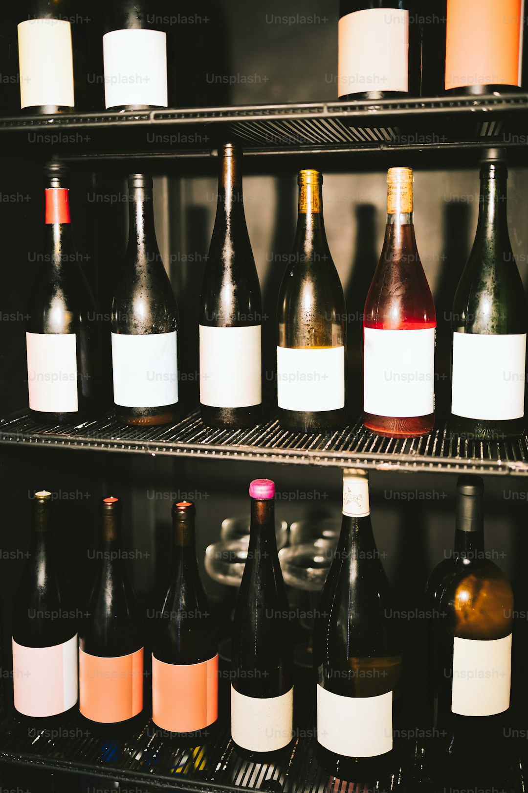 Wine bottles are stored in a dark, cool fridge.
