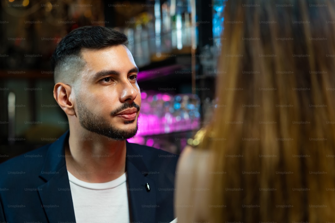 Asian woman standing at bar counter and talking to boyfriend with drinking alcoholic cocktail at nightclub. Male bartender mixologist preparing mixed alcoholic drink with decorate cocktail glass at bar counter