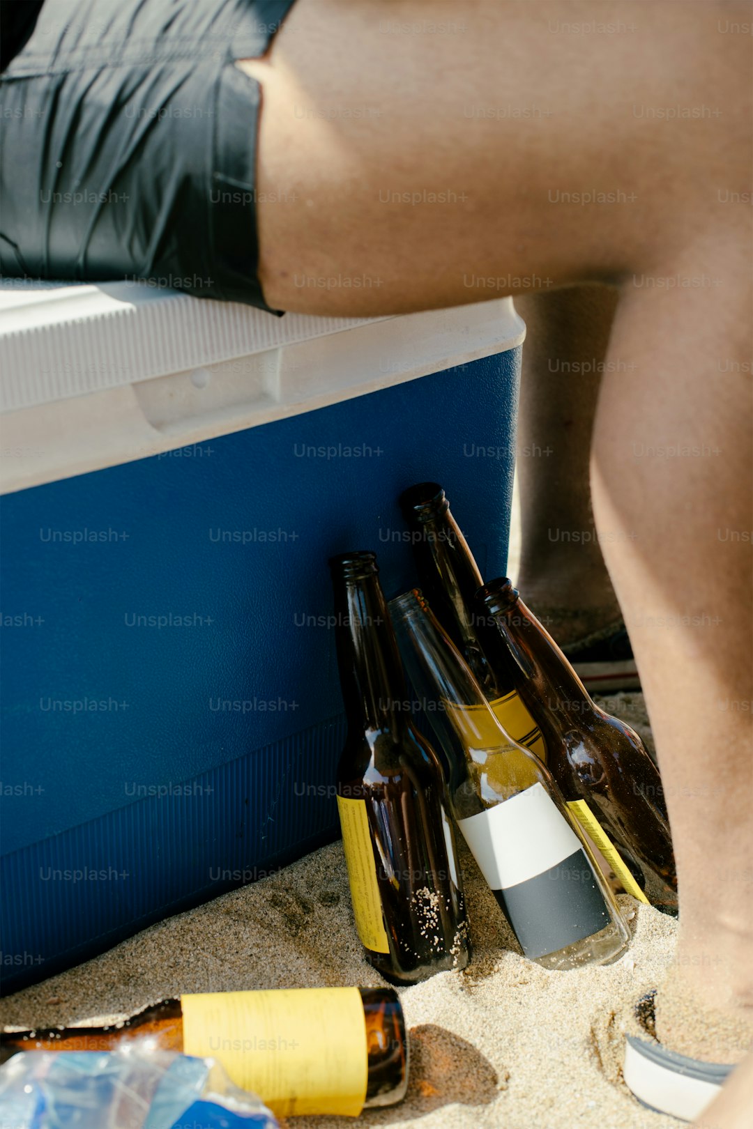 Empty beer bottles sit next to a cooler.