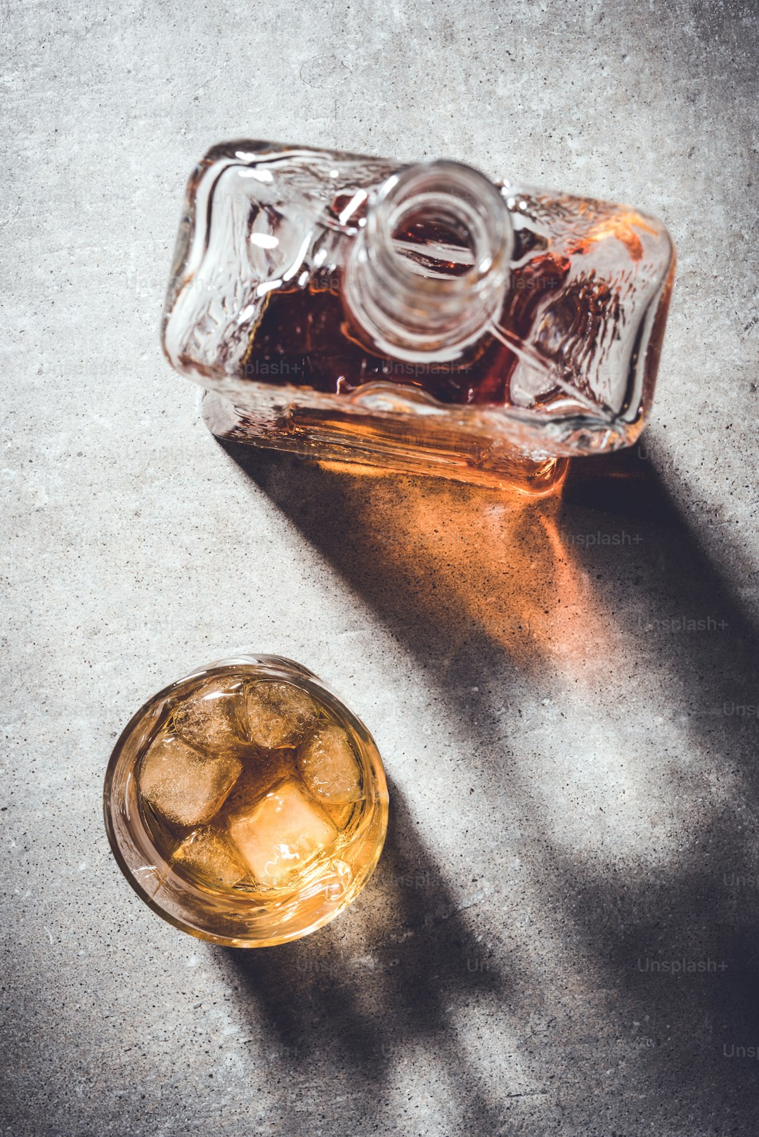 Whiskey bottle and whiskey glass on gray stone table. Close up