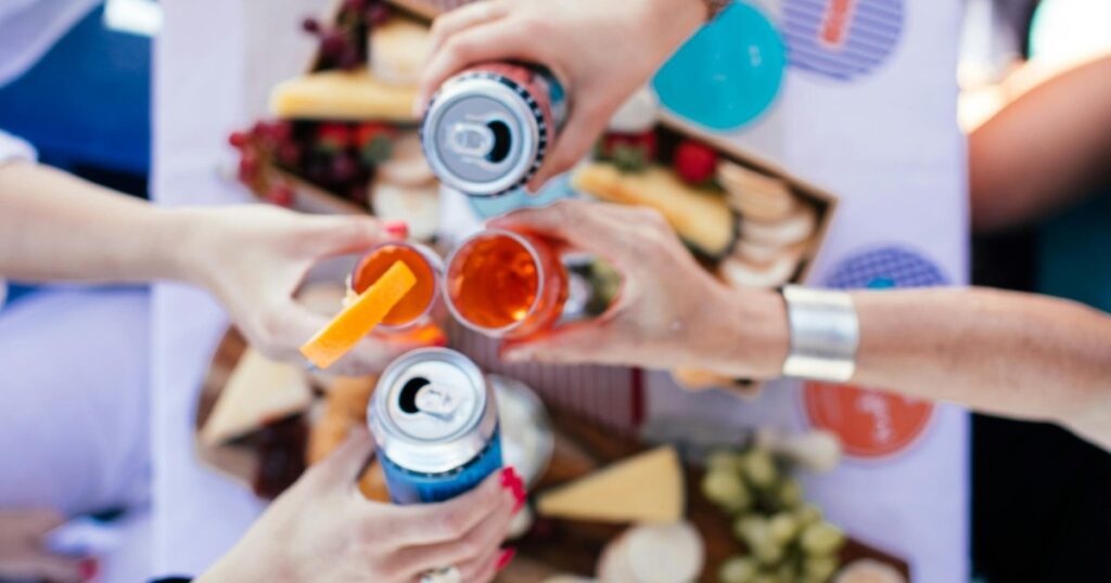 Friends toasting with canned cocktails outdoors